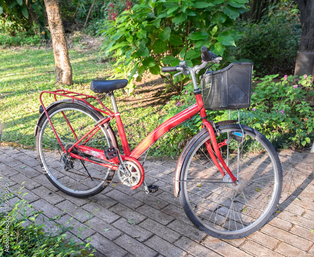 Antique cute red bike park on pathway in garden