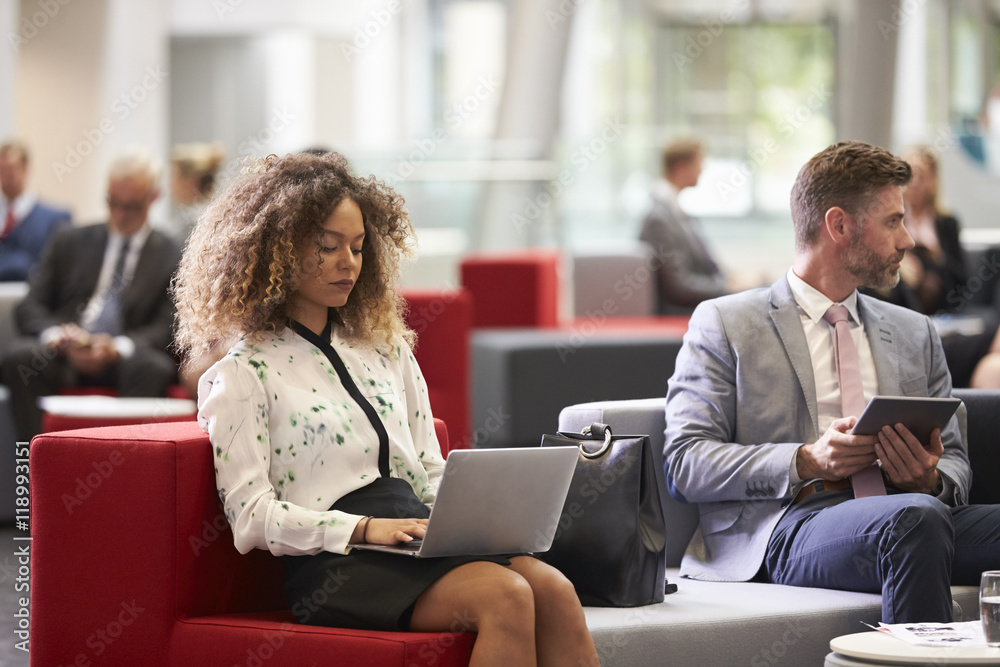 Businesspeople Using Digital Devices In Busy Office Lobby Businesspeople Using Digital Devices In Busy Office Lobby