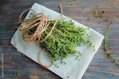 Heap of thyme twigs on linen tissue. Wooden table. Top view, Closeup. Copy space. 