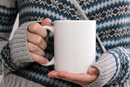 Fotografie, Obraz Girl in a warm cardigan is holding white mug in hands.