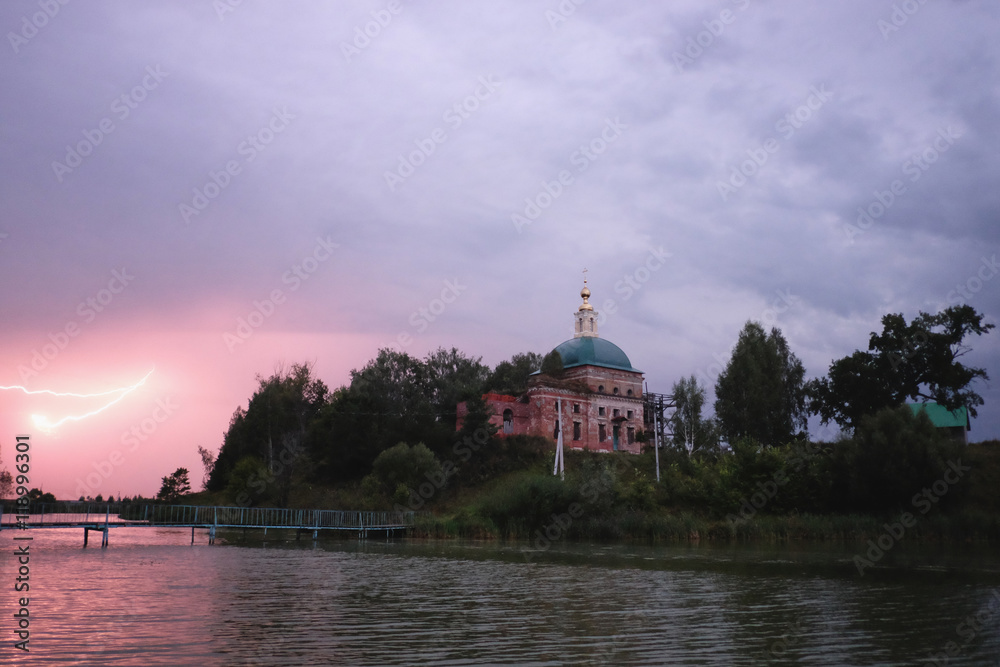  Ночной пейзаж с видом молнии над рекой и православного храма на берегу 
