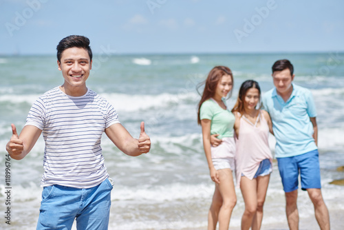 Asian cheerful young man enjoying his vacation with friends