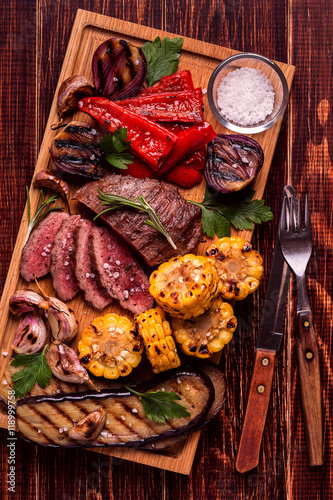 Grilled steak and vegetables on cutting board.