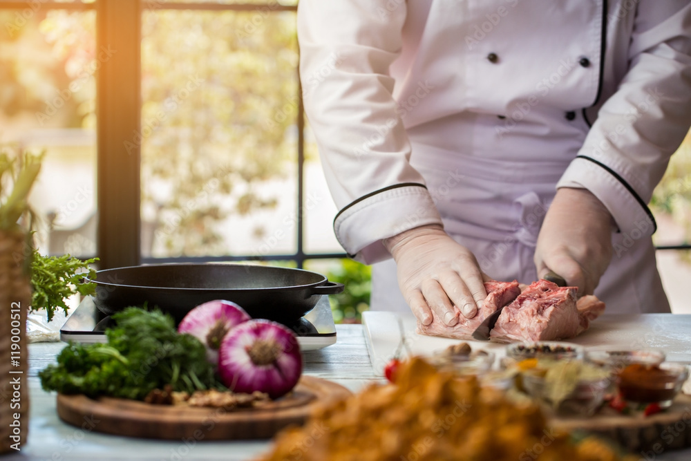 Man with knife cuts meat. Chef stands near frying pan. Pork meat for frying. Professional cook in the kitchen. Man with knife cuts meat. Chef stands near frying pan. Pork meat for frying. Professional cook in the kitchen.