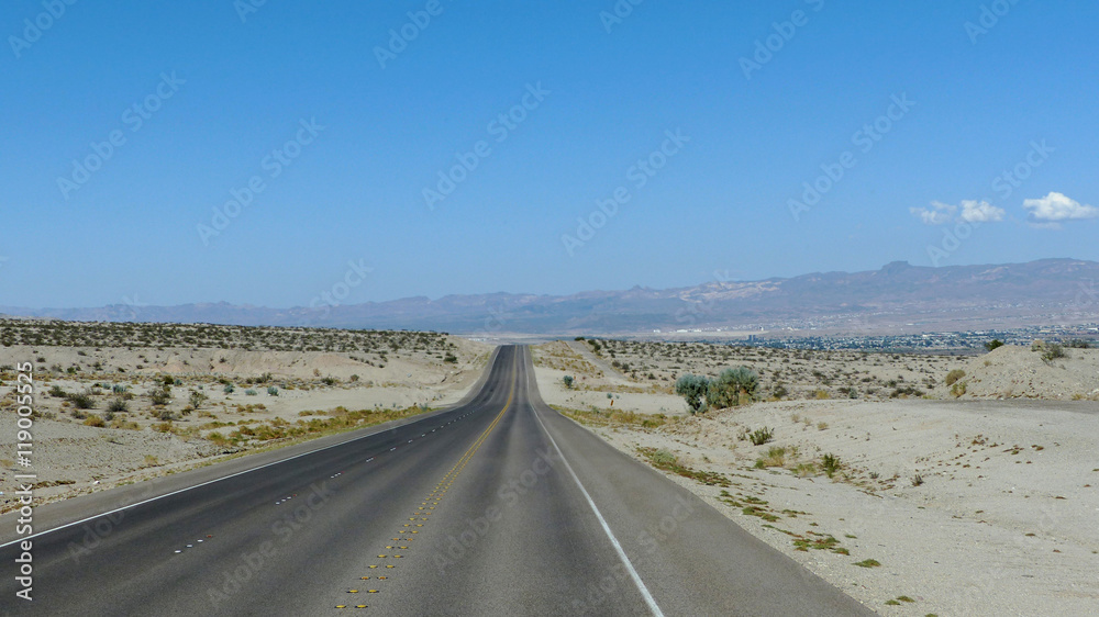 Highway durch die Wüste in Nevada/Lange, gerade Autobahn durch die Mojave-Wüste in Nevada, dreispurige Fahrbahn mit Markierung und Standstreifen, bergige Landschaft 