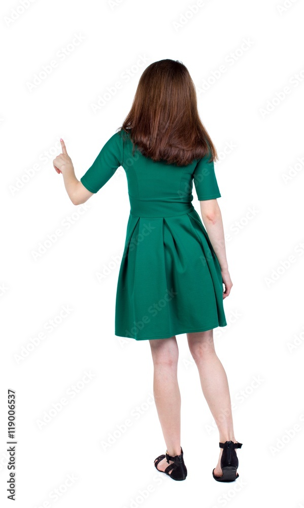 back view of woman. slender brunette in a green short dress is calling the index finger on the button. back view of woman. slender brunette in a green short dress is calling the index finger on the button.