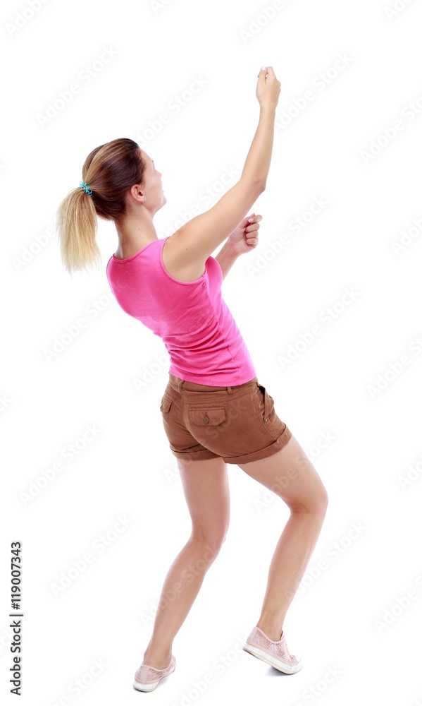 back view of standing girl pulling a rope from the top or cling to something. Isolated over white background. Sport blond in brown shorts hanging on a rope. back view of standing girl pulling a rope from the top or cling to something. Isolated over white background. Sport blond in brown shorts hanging on a rope.