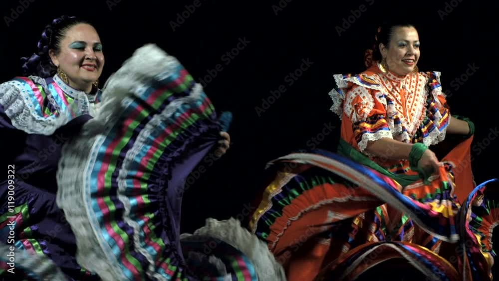 Slow motion shot of Mexican women in traditional dress dancing in the dark Slow motion shot of Mexican women in traditional dress dancing in the dark