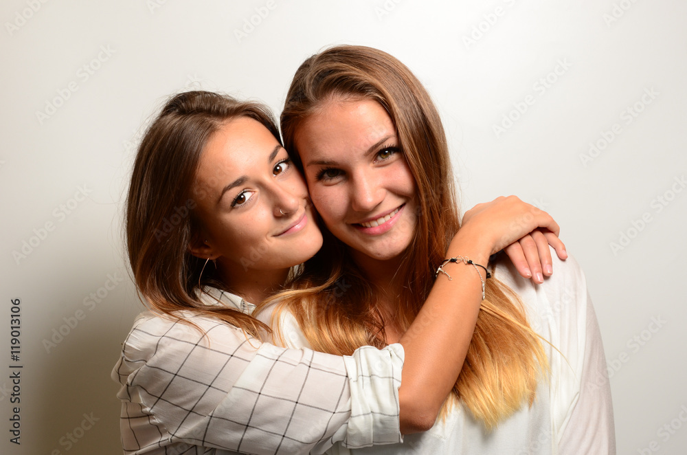 zwei mädchen rücken an Rücken mit ihren Handys, eine blickt neugierig über die Schulter
