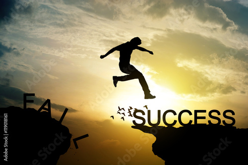 Man jumping over precipice on sunset background ,business succes