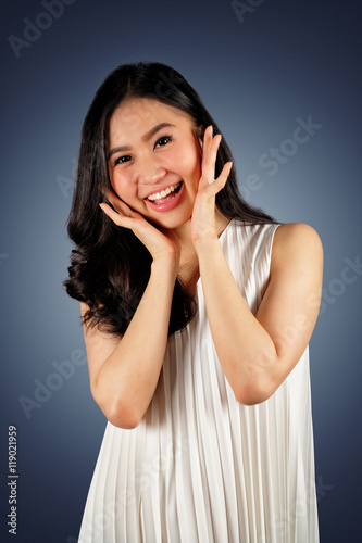 Happy woman wearing white dress looking at camera and dark blue