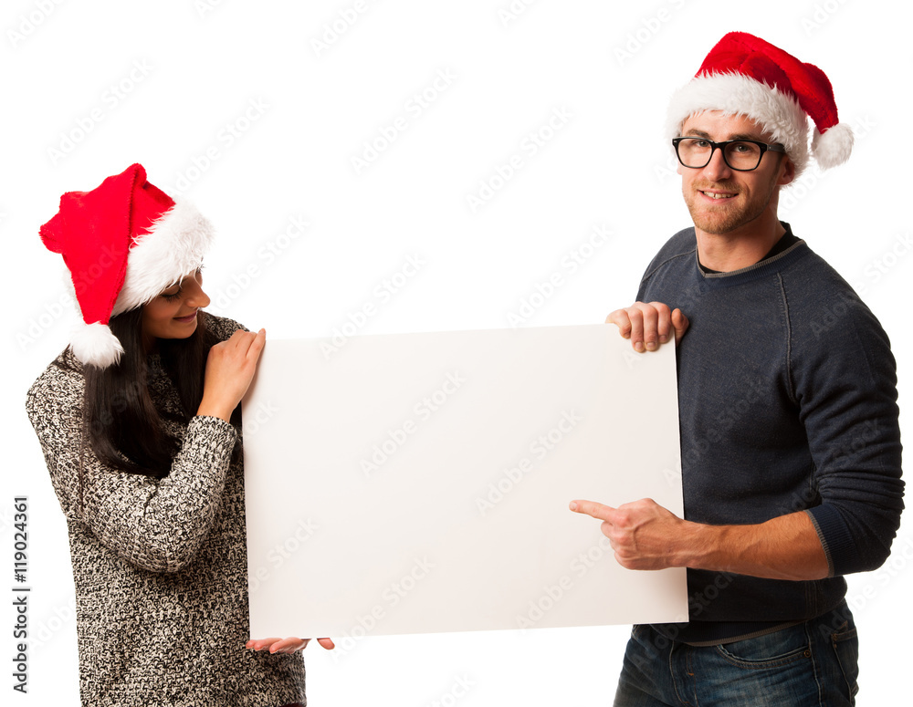 Young couple in santa hats holding blank board for advertisement