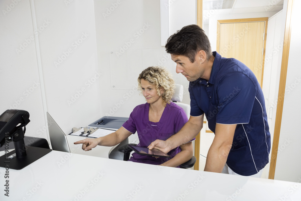 Obraz premium Dentists Using Computer At Reception Desk In Clinic