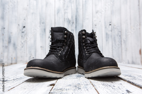 Footwear concept. Men's winter boots of black colour isolated on white wooden background. A pair of boots represented one near another.