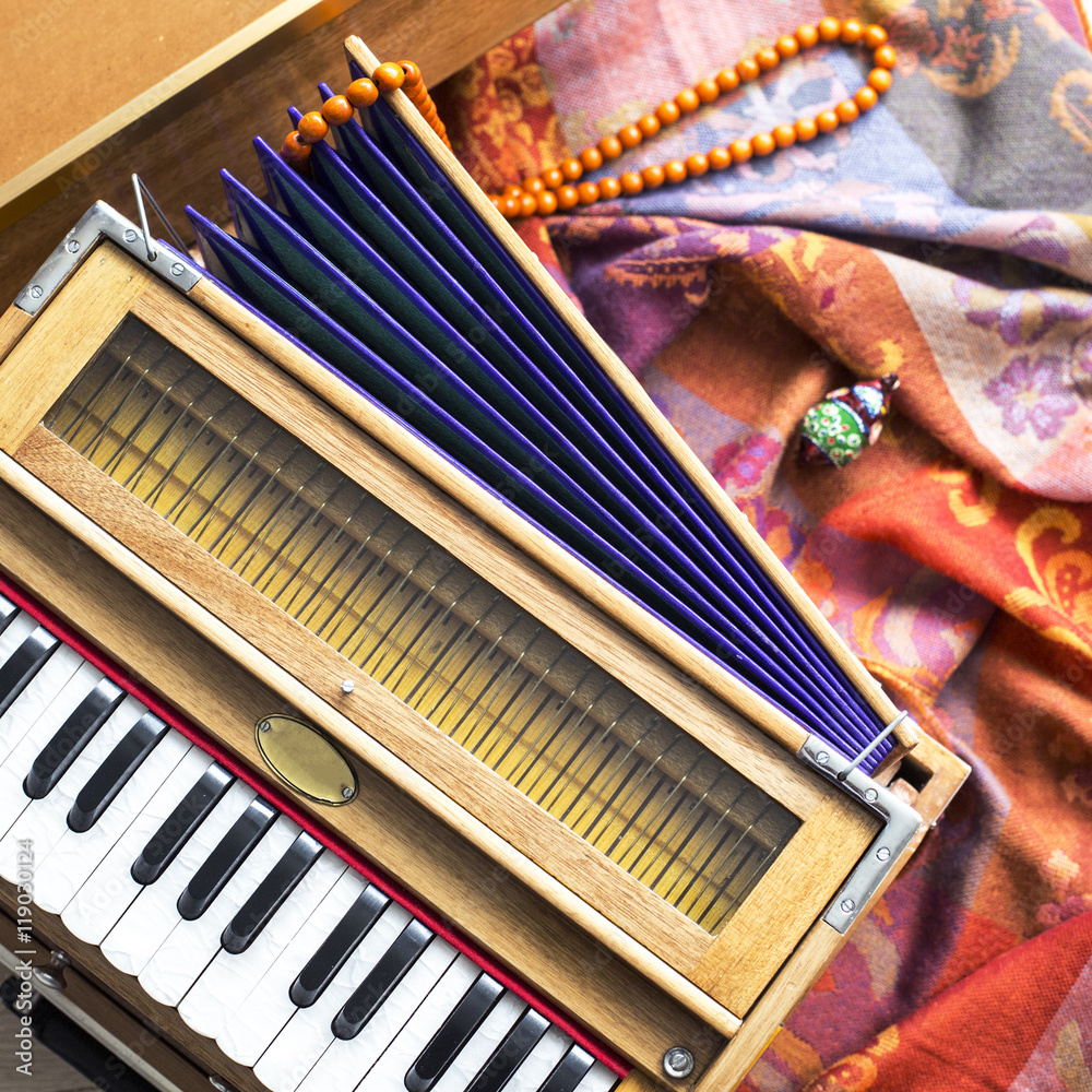 Indian harmonium, a traditional wooden keyboard instrument, close-up.  Bright colorful musical instrument on the patterned wrap Stock Photo |  Adobe Stock