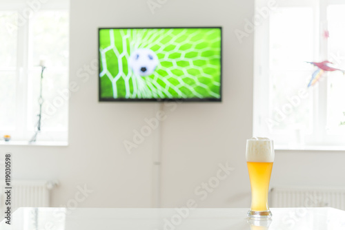 Fussball im Tornetz als Fernsehbild und ein Weißbier auf einem Tisch