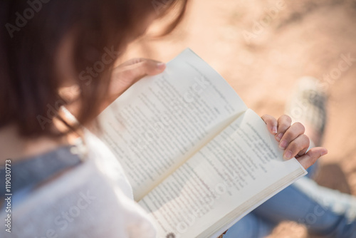 A young woman reading a book. Book in woman hands