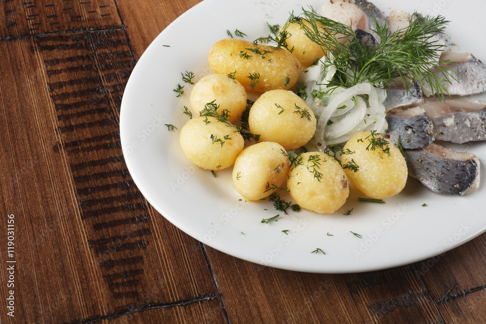 Herring fish with young potato on white plate. wooden background. Herring fish with young potato on white plate. wooden background.