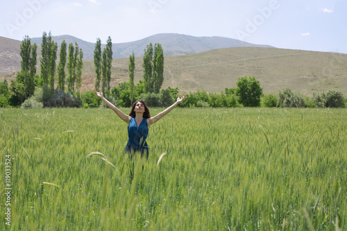 Happy woman in the young green wheat