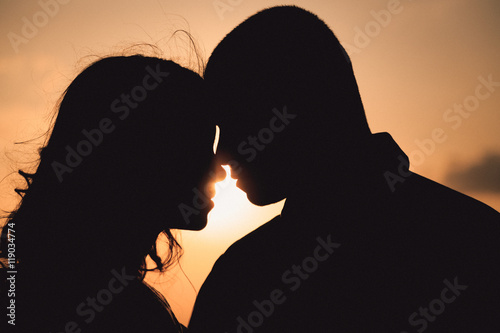 Silhouettes of wonderful couple standing thoughtful in the rays