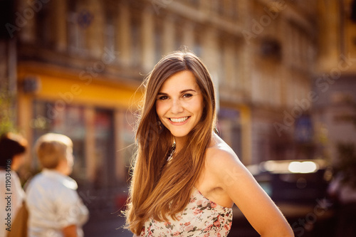 Summer sun makes a halo over the head of smiling woman