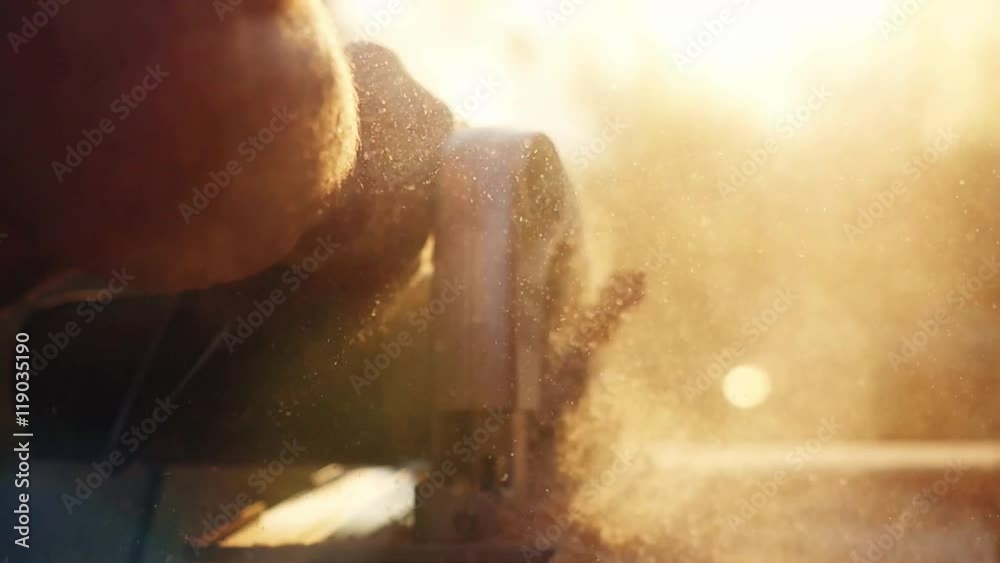 Man is craft working at a work bench with power tools in slowmotion during sunset with beautiful lens flare. 1920x1080