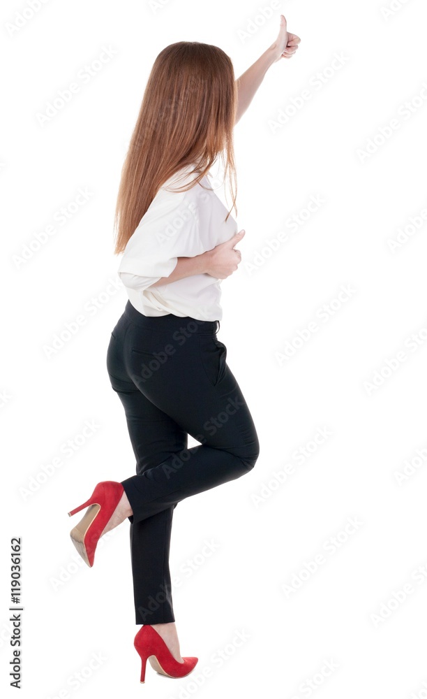 back view of standing young redhead business woman showing thumb up. beautiful businesswoman in black suit gesturing ok sign. Rear view people collection. backside view of person. Isolated over back view of standing young redhead business woman showing thumb up. beautiful businesswoman in black suit gesturing ok sign. Rear view people collection. backside view of person. Isolated over