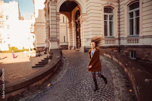 Girl in leather shoes and orange coat runs around the palace