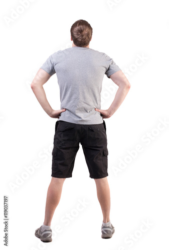Back view of handsome man in t-shirt and  shorts  looking up.   Standing young tourist. Rear view people collection.  backside view of person.  Isolated over white background. her hands on her hips © ghoststone
