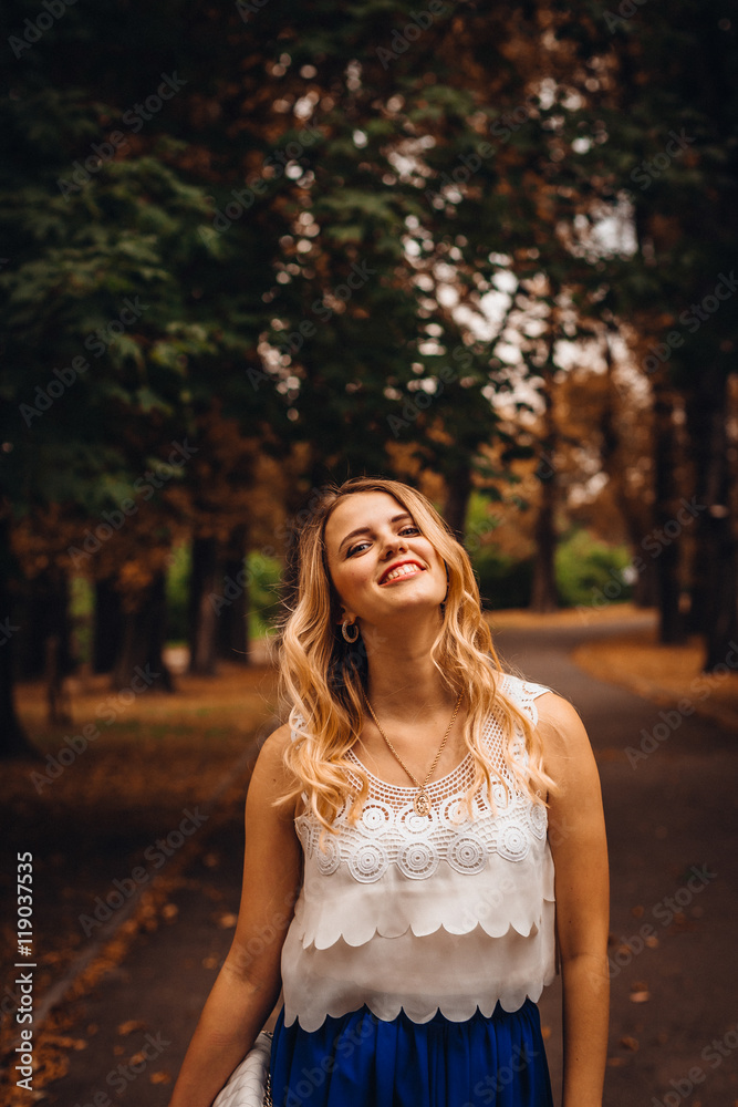 Charming woman in white shirt and blue skirt stands in the autum Charming woman in white shirt and blue skirt stands in the autum