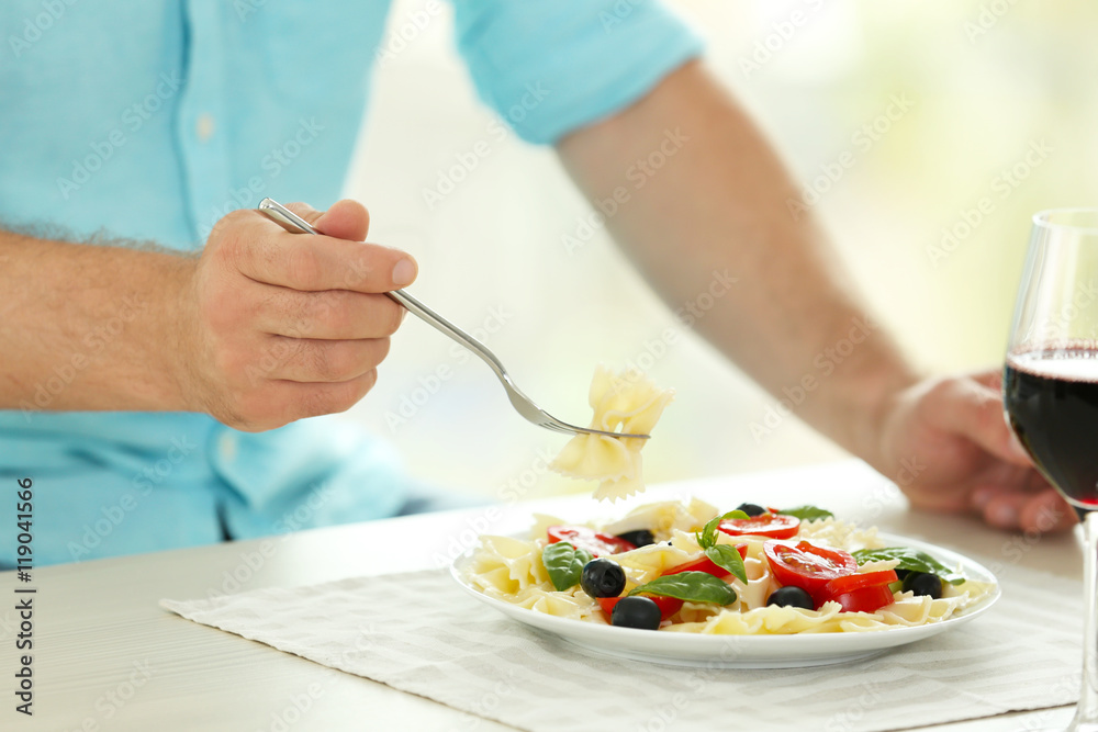 Man eating delicious pasta in restaurant