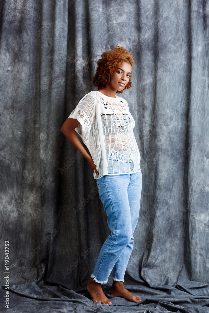 Young beautiful african girl posing over grey cloth background. Young beautiful african girl posing over grey cloth background.