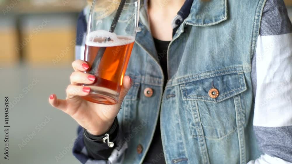 Pretty girl drinking beer and smiling to the camera, steadycam shot
