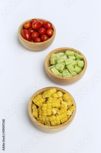 Vegetables in round wooden bowl on white background, steam sweet corn, cucumber and tomato
