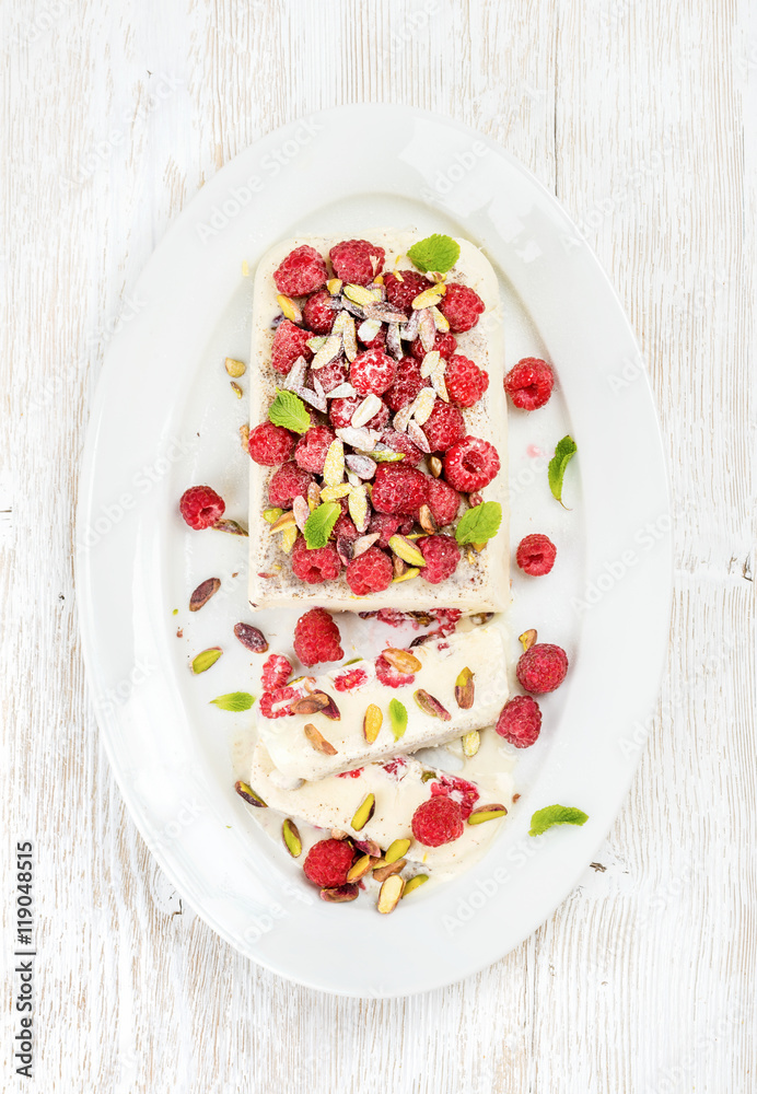 Homemade semifreddo with pistachio and raspberry in oval dish over old white painted wooden background, top view Homemade semifreddo with pistachio and raspberry in oval dish over old white painted wooden background, top view