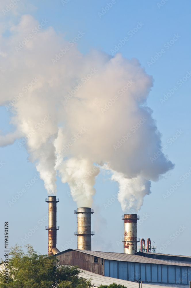 three of factory smokestack against morning sunlight