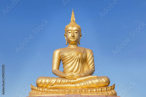 big golden buddha statue sitting in thai temple on blue sky background