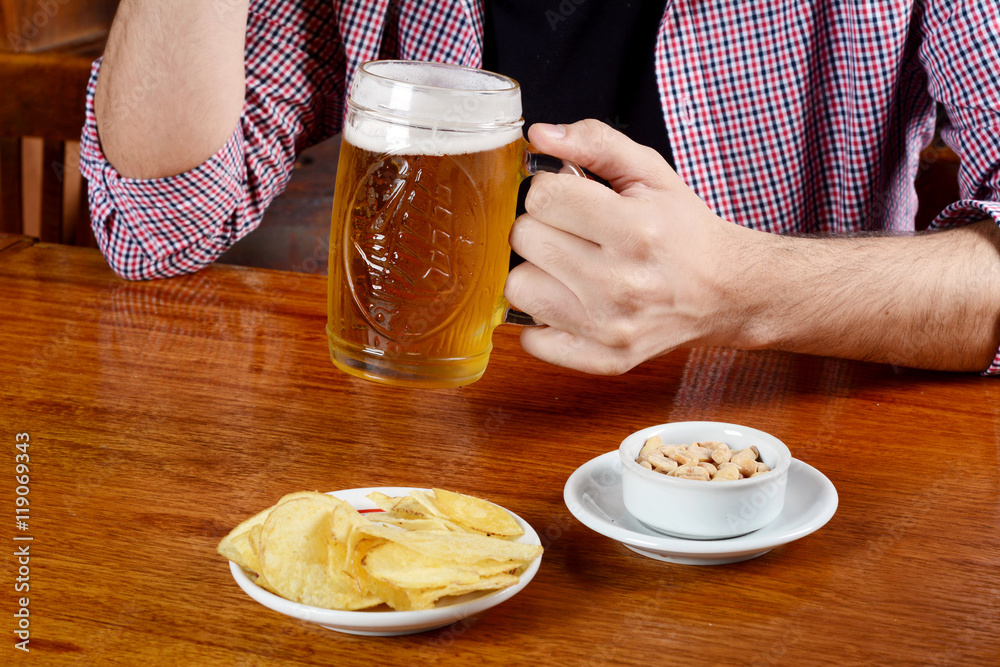 Latin man drinking beer and eating snacks at a bar Latin man drinking beer and eating snacks at a bar