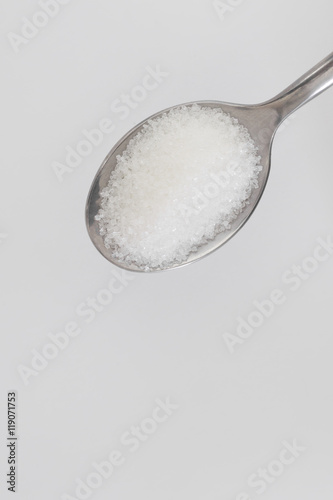white sugar in steel spoon on white background