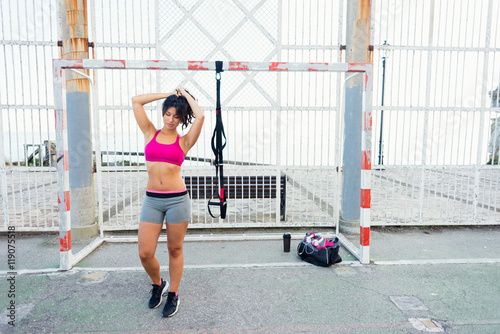 Sporty young woman getting ready for fitness trx workout with straps. Healthy lifestyle and training outside.