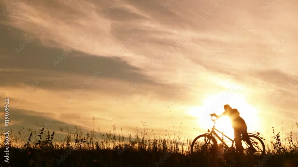 9 years old boy riding bike then celebrating his success with funny dance. Silhouette of little jumping happy kid with hands up at sunset sky background. Real time video footage. 9 years old boy riding bike then celebrating his success with funny dance. Silhouette of little jumping happy kid with hands up at sunset sky background. Real time video footage.