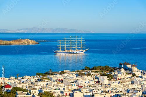 Wooden sailboat on sea with Mykonos town in foreground, Mykonos island, Greece