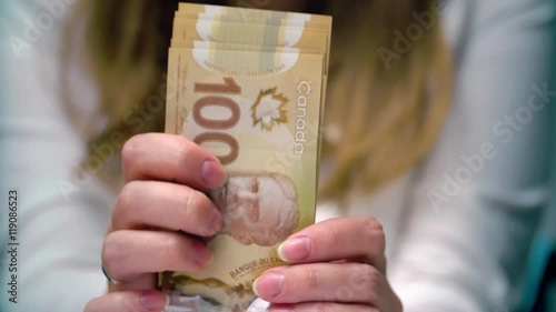 View of a woman Counting Many Canadian 100 bills, polymer plastic type, Woman not happy about not having enough money