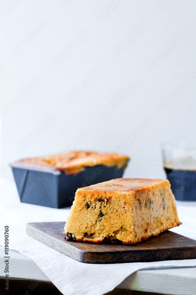 Orange chocolate chip loaf cake. Dark wooden board. White background. Free text space. Light food photography. Orange chocolate chip loaf cake. Dark wooden board. White background. Free text space. Light food photography.