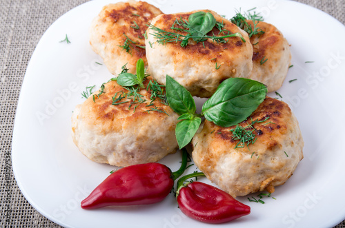 Rissole of minced chicken on a white plate with red pepper