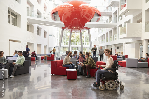 Student in wheelchair and colleagues in university lobby photo