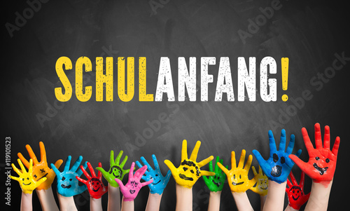 lachende angemalte Kinderhände vor Kreidetafel mit dem Wort Schulanfang! photo