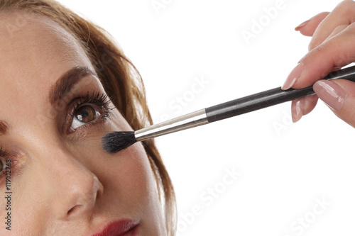 jolie femme se faisant maquiller avec un pinceau autour des yeux photo