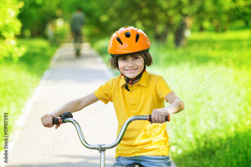 A kid at bike in city park in summer day