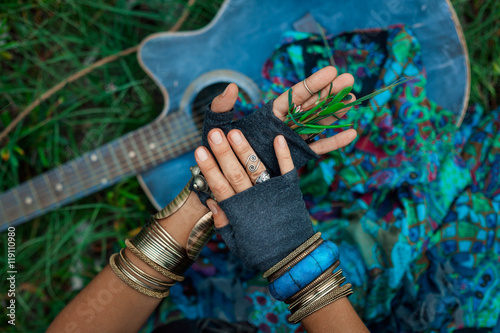 close up photo of gypsy girl hands with guitar on green grass